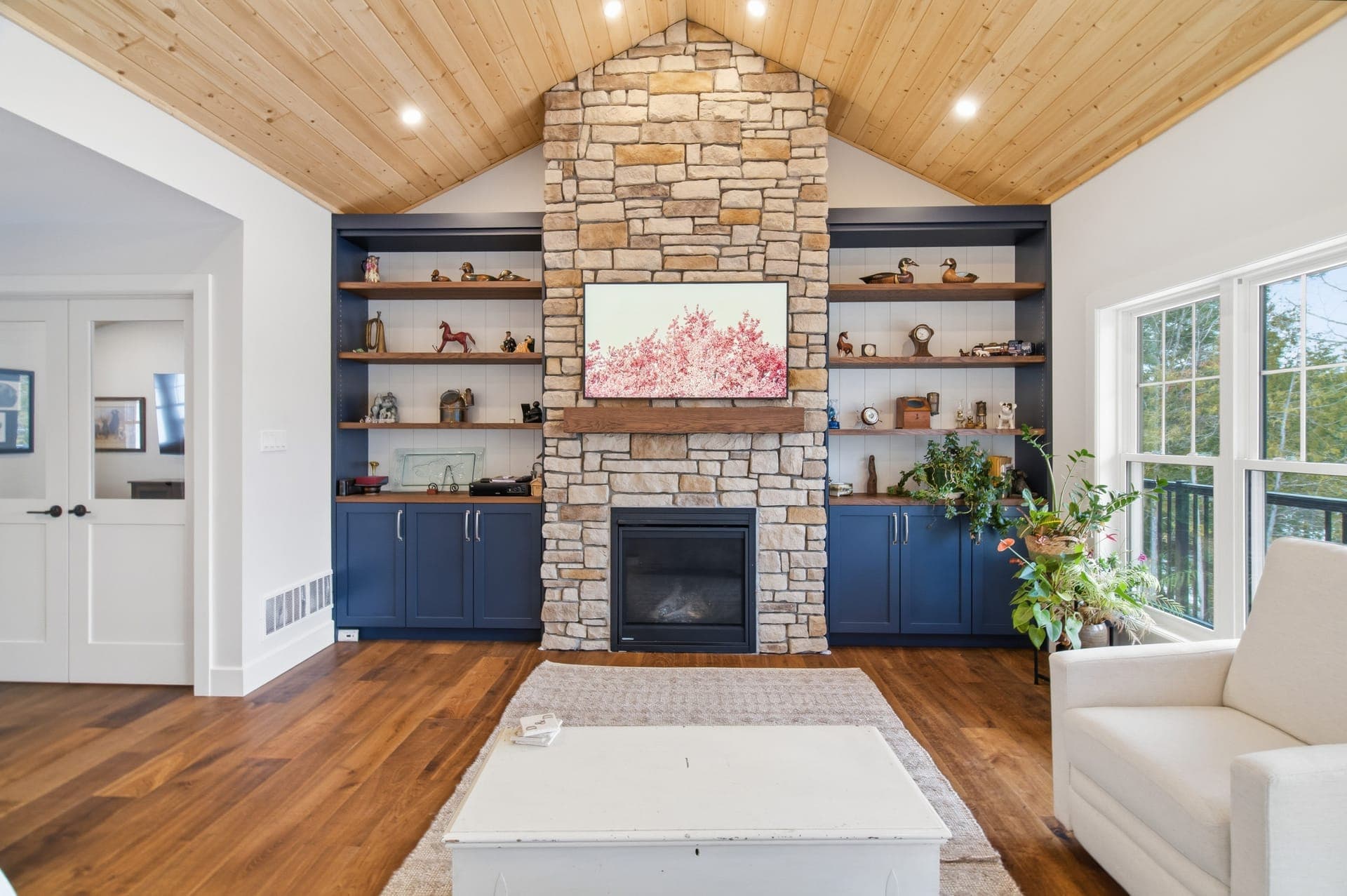 Custom home living room with stone fireplace and vaulted wood ceiling