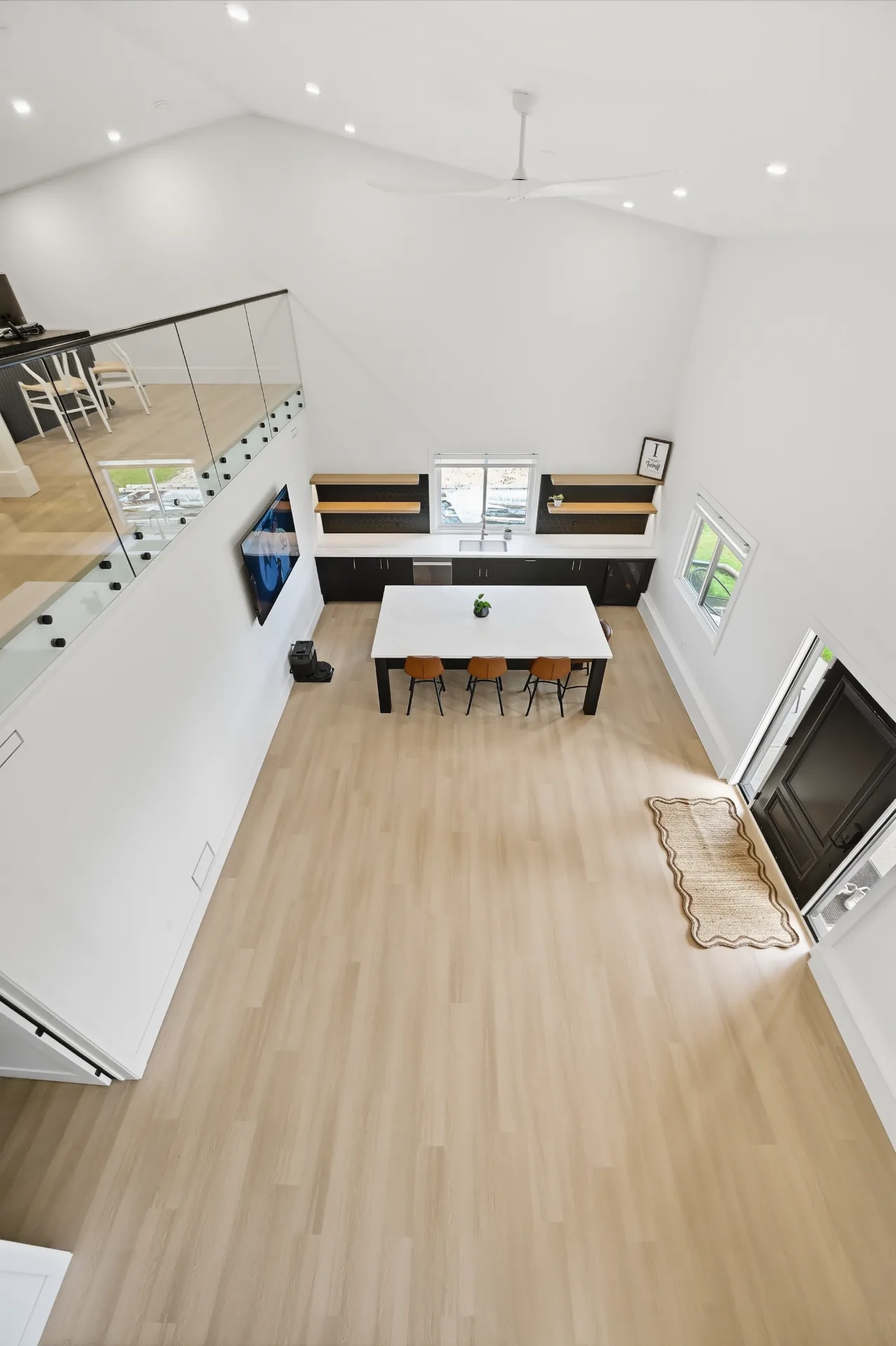 Open-plan kitchen and dining with glass-railed mezzanine above